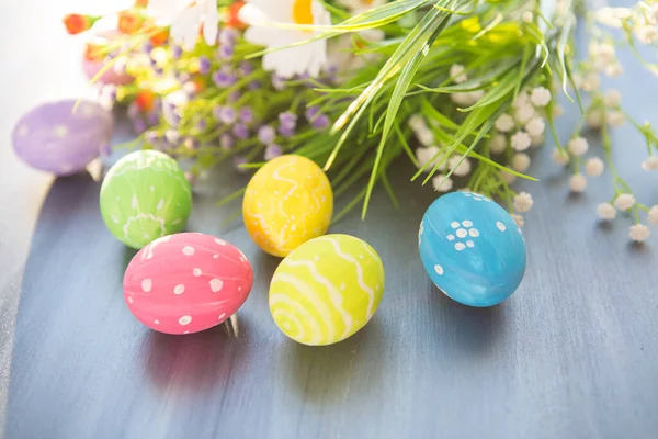 Renkli paskalya süslemesi ve gri ahşap bir masada çiçekler..