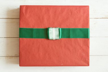 Beyaz tahta arka planda kurdeleli kırmızı hediye kutusu.