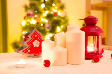 Beyaz tahta üzerinde birkaç beyaz noel mumu oturma odasındaki Noel ağacına karşı..