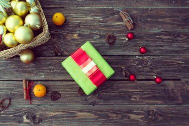 Noel yeşili hediye paketi ve ahşap arka planda kırmızı kurdele. Xmas ve Mutlu Yıllar kompozisyonu. Düz yatış, üst görünüm.