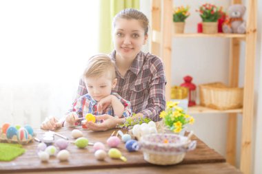 Paskalya yumurtası boyarken mutlu zamanlar. Paskalya konsepti. Mutlu anne ve tatlı çocuğu yumurtaları boyayarak Paskalya için hazırlanıyorlar..