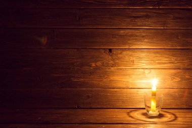 Eski ahşap arka planda yanan bir mum ve kopyalama alanı.