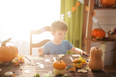 Küçük çocuk Cadılar Bayramı için kurabiye dekore etti. Tatlı çocuk Cadılar Bayramı kutlamasına hazırlanıyor..
