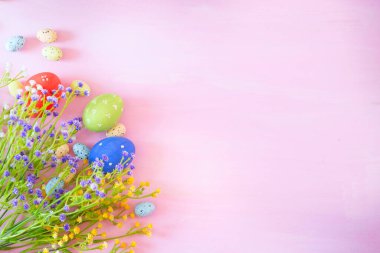 Pembe ahşap masada çiçekli Paskalya yumurtaları.