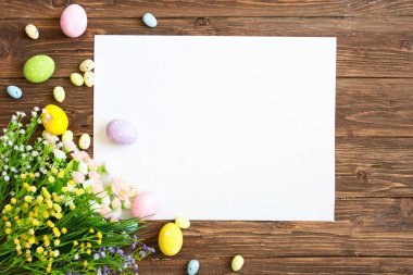 Kahverengi ahşap arka planda Paskalya süslemeleri olan boş bir çarşaf. Paskalya tebrik kartı.