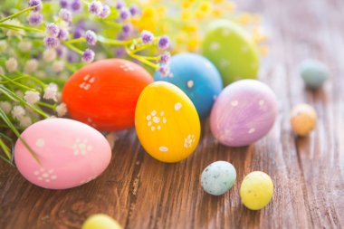 Kırsal ahşap arka planda çiçekli Paskalya yumurtaları ve dalları.