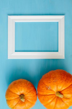 Mavi ahşap arka planda beyaz çerçeveli turuncu balkabakları Şükran Günü ve Cadılar Bayramı konsepti. Yukarıdan bak. Üst Manzara. Metin ve tasarım için alanı kopyala. Akıllı telefon için dikey resim