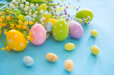 Paskalya yumurtaları. Elle boyanmış, samanla süslenmiş yumurta, mavi ahşap..