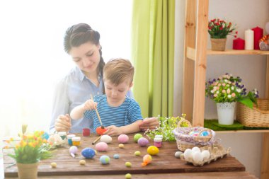 Paskalya konsepti. Mutlu anne ve tatlı çocuğu yumurtaları boyayarak Paskalya için hazırlanıyorlar..