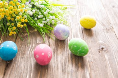 Ahşap arka planda pastel renklerle boyanmış Paskalya yumurtaları.