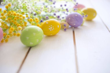 Tahta arka planda bahar çiçekleri olan Paskalya yumurtaları. Süslü Yumurta Tatili sanat tasarımı arkaplanı.