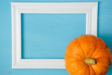 Mavi ahşap arka planda beyaz çerçeveli turuncu balkabakları Şükran Günü ve Cadılar Bayramı konsepti. Yukarıdan bak. Üst Manzara. Metin ve tasarım için boşluk kopyala