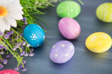 Boyanmış paskalya süsü ve gri ahşap bir masa üzerinde çiçekler..