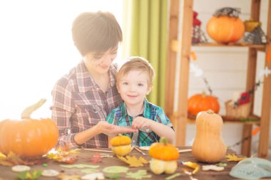 Mutlu Cadılar Bayramı. Küçük oğluyla birlikte genç bir kadın mutfakta Cadılar Bayramı 'na hazırlanıyor. Anne ve oğlu balkabağıyla eğleniyor..