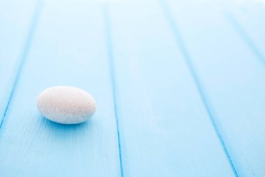 Saf beyaz taş mavi, pürüzsüz ahşap bir masa üzerinde.