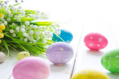 Paskalya yumurtaları, Paskalya çiçekleri. Ahşap masada renkli paskalya yumurtaları ve çiçekler.