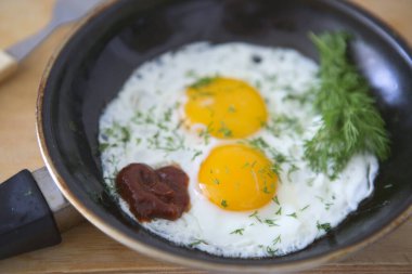 Tavada yumurta ve ahşap masa sapı.