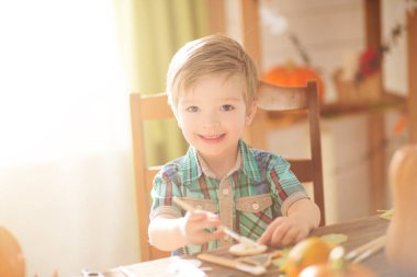 Mutlu Cadılar Bayramı konsepti. Şirin küçük mutlu çocuk Cadılar Bayramı için balkabağını kapalı bir masaya oyuyor..