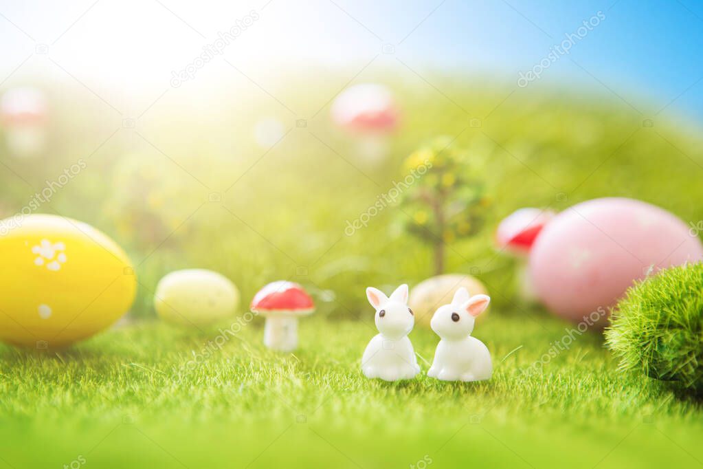Little Easter bunny toys and Easter eggs on a green grass.