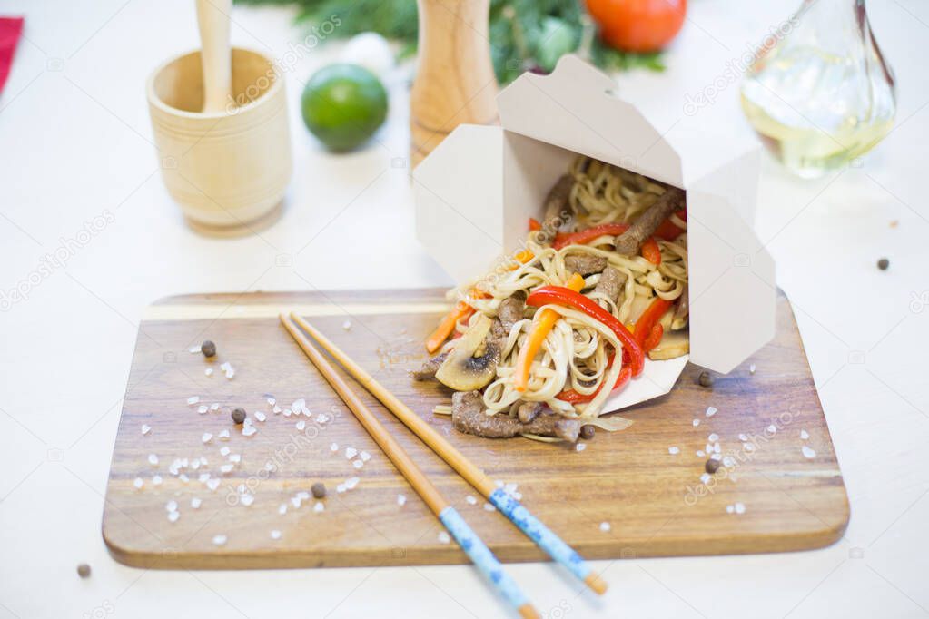 Noodles with vegetables in take-out box on wooden table Healthy and tasty food.