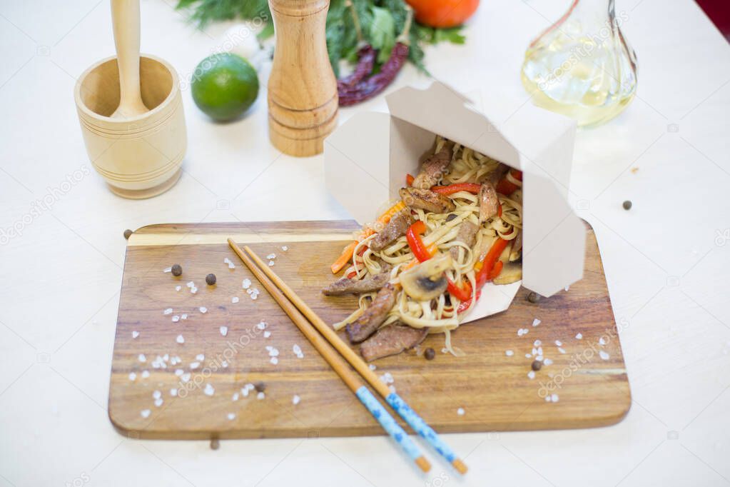 Noodles with vegetables in take-out box on wooden table Healthy and tasty food.