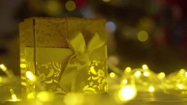 Noel hediyesi masanın üzerinde Noel ağacının arka planında.