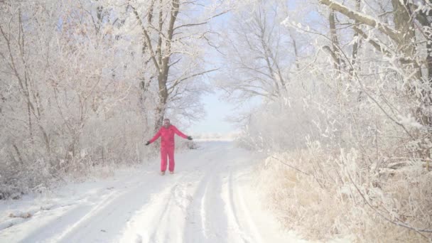 Человек идет по зимнему лесу с заснеженными деревьями в прекрасное морозное утро — стоковое видео