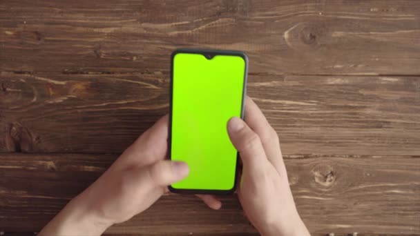 Male hands with a smartphone with a chroma key on the table. View from above — Stock Video