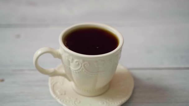 Moldura estática. Uma xícara com café quente fica em uma mesa de madeira branca — Vídeo de Stock