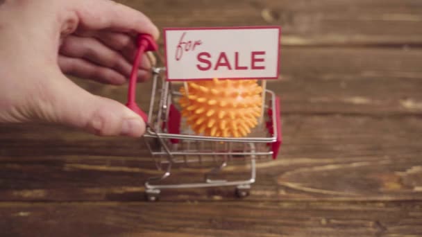 Carrinho de compras pequeno com bola em forma de coronavírus na mesa — Vídeo de Stock