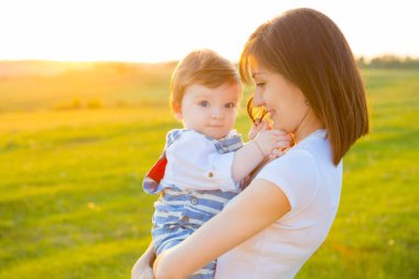 Anne ve sevgili oğlu güneşli arazide kasıtlı güneş parlıyor. Mutlu aile kavramı.