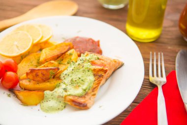 Ahşap bir masada fırında patates ve somon filetosu.