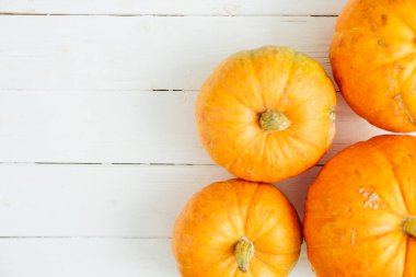 Beyaz ahşap arka planda fotokopi alanı olan balkabakları. Şükran Günü ve Cadılar Bayramı konsepti. Yukarıdan bak. Üst Manzara. Metin ve tasarım için boşluk kopyala