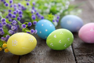 Ahşap arka planda çiçekli el yapımı Paskalya yumurtaları.