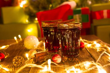 İki bardak ılık sıcak kış içeceği Noel şarabı ya da beyaz ahşap arka plan masasında yılbaşı süsleri ve ışıkları olan köknar ağacına karşı sıcak çay..