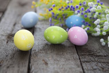 Paskalya arkaplanı, renkli yumurtalar ve odunların üzerinde çiçekler. Mutlu Paskalyalar.