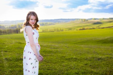 Gün batımında tarlada gülümseyen güzel bir kadın. Tarlada beyaz elbiseli güzel manken kız..