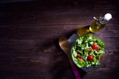 Ahşap bir masada cam bir kasede renkli taze sebze salatası. Sağlıklı yaşam tarzını ve basit yiyecekleri hesaba katın.