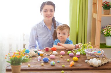 Paskalya konsepti. Mutlu anne ve tatlı çocuğu yumurtaları boyayarak Paskalya için hazırlanıyorlar..