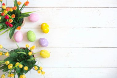 Beyaz ahşap arka planda çiçekli Paskalya yumurtaları.