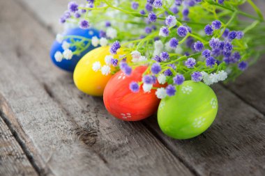 Doğal ahşap bir yüzeyde güzel kır çiçekleri olan Paskalya yumurtaları. Paskalya geçmişi. Mutlu Paskalyalar.