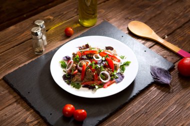 Kızarmış ciğer, soğanlı ve domatesli siyah taş zemin..