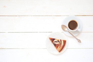 Bir parça çikolatalı kek ve beyaz ahşap masada bir fincan kahve. Restoran veya kafe menüsü arkaplanının üst görünümü.