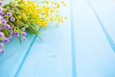 Renkli sarı, beyaz ve leylak bahar çiçekleri mavi boyalı ahşap tahtalar üzerinde.