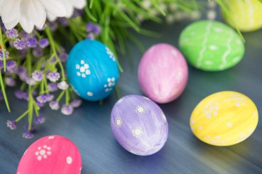 Paskalya yumurtaları ve çiçekler gri ahşap kalaslarda.