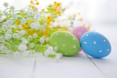 Paskalya yumurtaları ve çiçekler arka planda. Paskalya geçmişi. Paskalya sembolü. Paskalya avı. Boşluğu kopyala