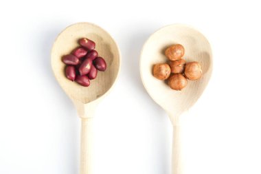 Tahta kaşıkta fıstık ve fındık, beyaz arka planda izole edilmiş.