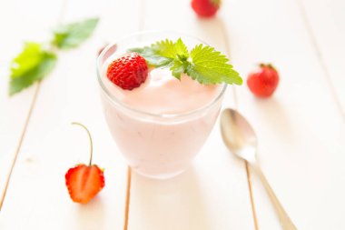 Beyaz ahşap bir masada çilekli taze ev yapımı yoğurt..