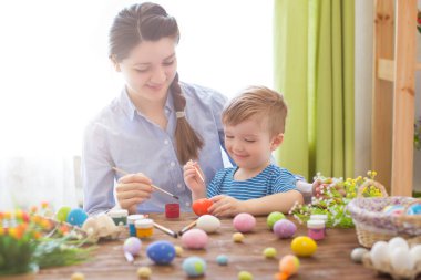 Paskalya konsepti. Mutlu anne ve tatlı çocuğu yumurtaları boyayarak Paskalya için hazırlanıyorlar..