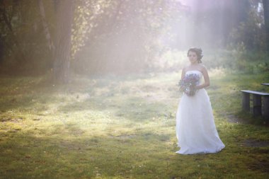 Ormanda güzel bir gelin. Güneş ışınları ormanda yürüyen kadını dövüyor.